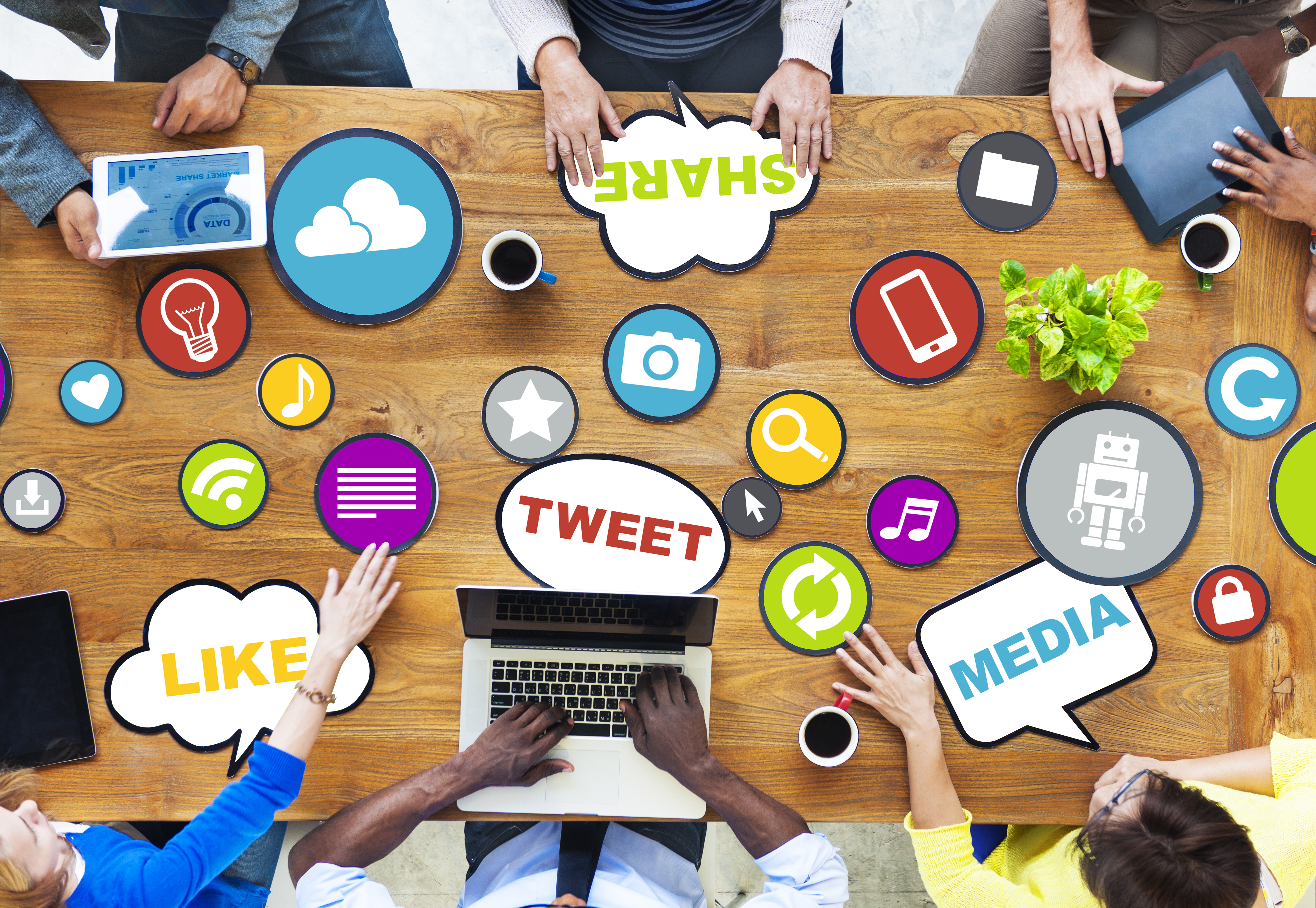 Group of people sitting at table with their devices and multiple posters on social media